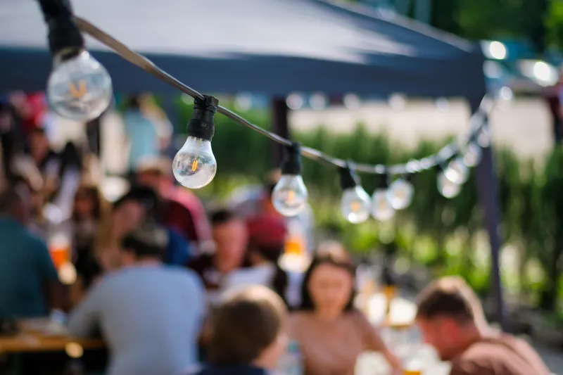Vereinsfest unter Lichterketten mit Gästen an Biertischen