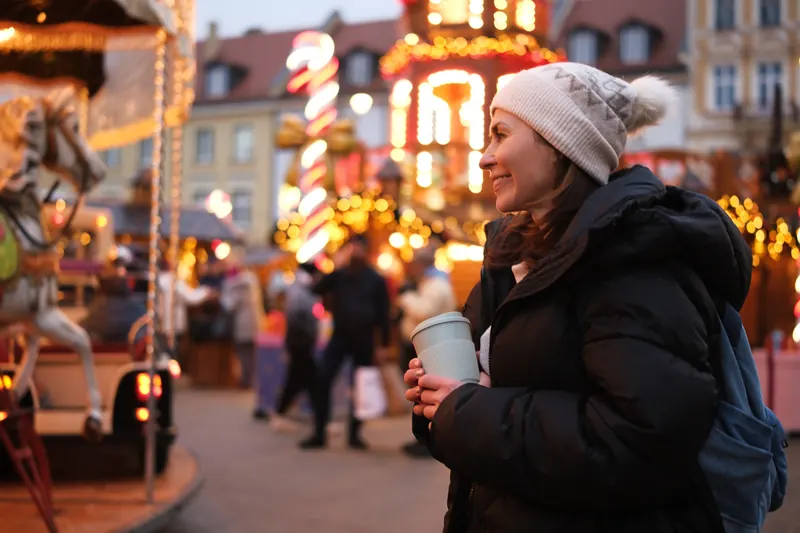 Besucherin auf einem Weihnachtsmarkt mit Karussell